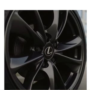 May include: A dark grey metallic alloy car wheel featuring a multi-spoke design with a glossy finish. The centre cap displays the silver Lexus logo, and the wheel is mounted with a black rubber tyre, showcasing a sleek and modern automotive aesthetic.