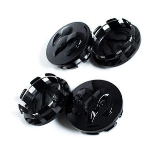May include: Four black wheel center caps with a glossy finish. Each cap features a raised ram logo in the center and a checkered pattern around the edge. The caps are set against a white background.
