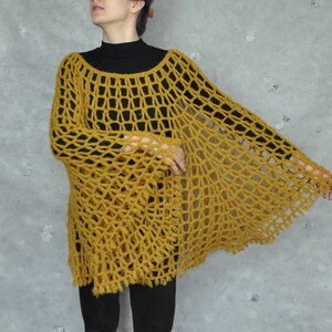 Peut inclure: Un poncho en crochet jaune moutarde &agrave; la maille l&acirc;che et ouverte, avec une silhouette ample et fluide.