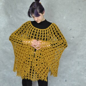 Peut inclure: Un poncho en crochet jaune moutarde &agrave; maille l&acirc;che et ouverte, avec une bordure frang&eacute;e.