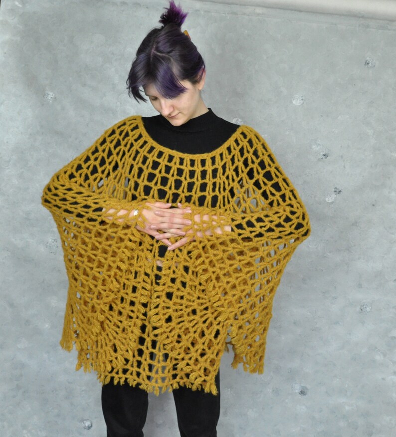 Peut inclure: Un poncho en crochet jaune moutarde &agrave; maille l&acirc;che et ouverte, avec une bordure frang&eacute;e.