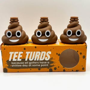 May include: Three brown novelty golf ball markers shaped like smiling poop emojis. The markers sit atop a box with the text "TEE TURDS" and the tagline "because all golfers have a -shittee day at some point."