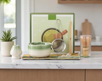 May include: A matcha tea set with a green and white ceramic bowl, a bamboo whisk, a sifter, and a bamboo scoop. The set includes a matcha bowl, a whisk holder, and a box with a matcha illustration.