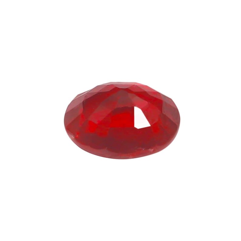 May include: A faceted, oval-shaped, deep red gemstone. The gem has a polished surface with multiple facets that reflect light, creating a sparkling effect. The gemstone is set against a plain white background.