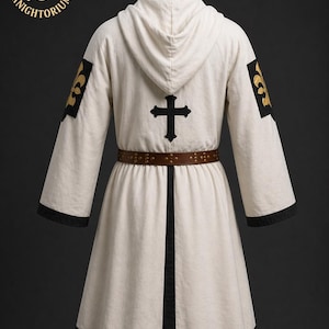 May include: Cream-colored hooded robe with black trim and a brown belt. The back features a black cross and gold fleur-de-lis patches on the sleeves. The robe is from Knightorium.