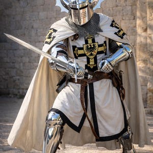 May include: A knight in full armor, holding a sword. The knight wears a silver helmet with decorative horns, a white tunic with black trim, and a cape. The armor is highly polished, reflecting the light. The image includes the text "Knightorium".