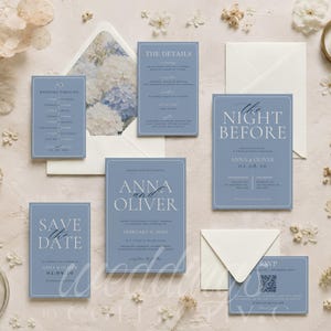 May include: A set of dusty blue wedding stationery including a Save the Date, wedding invitation, details card, timeline, and RSVP card with a QR code. The cards feature white serif typography and are accompanied by cream-colored envelopes.