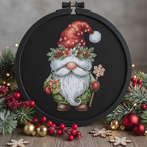 May include: A cross-stitch of a Christmas gnome in a black hoop. The gnome has a red hat with white dots, a long white beard, and a green coat. He holds a snowflake staff and a gift. Festive decorations surround the hoop.