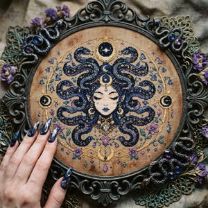 This celestial Medusa cross stitch pattern features a mystical serpent goddess surrounded by flowing cosmic snakes, golden moon symbols, celestial ornaments, and delicate floral accents. Inspired by mythology and dark fantasy aesthetics, the design transforms Medusa into a peaceful moonlit queen filled with elegance and magical energy. Deep navy blue tones blend with soft lavender, dusty pink, and gold celestial details to create an enchanting embroidery composition perfect for gothic home décor
