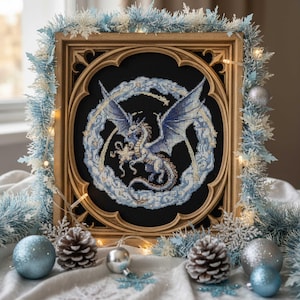 May include: A framed cross-stitch artwork depicting a blue and white dragon on a black background. The artwork is in a decorative gold-coloured frame, surrounded by blue and white garland, baubles, and pine cones. The theme is fantasy and winter.