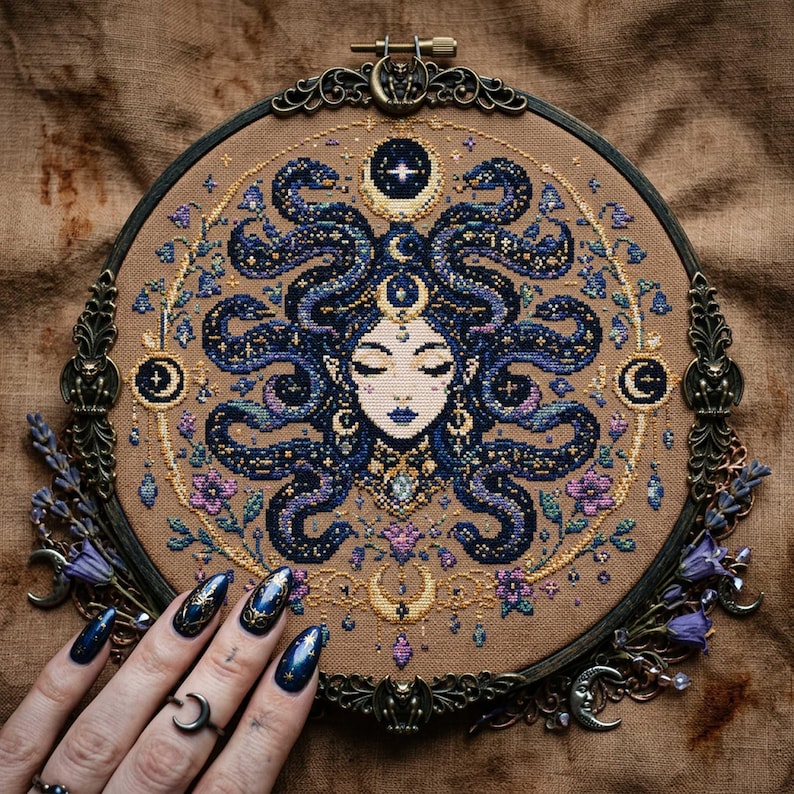 This celestial Medusa cross stitch pattern features a mystical serpent goddess surrounded by flowing cosmic snakes, golden moon symbols, celestial ornaments, and delicate floral accents. Inspired by mythology and dark fantasy aesthetics, the design transforms Medusa into a peaceful moonlit queen filled with elegance and magical energy. Deep navy blue tones blend with soft lavender, dusty pink, and gold celestial details to create an enchanting embroidery composition perfect for gothic home décor