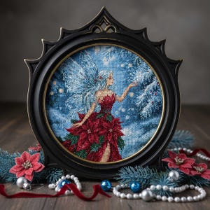 Può includere: Un'opera d'arte a punto croce incorniciata raffigura una fata in un abito di poinsettia rosso con ali ghiacciate, su uno sfondo blu nevoso. La cornice nera ha un design ornato. Elementi decorativi includono fiori rossi, ornamenti blu e una ghirlanda di perle.