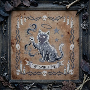 Könnte beinhalten: Kreuzstichkunst mit einer grauen Katze mit Heiligenschein, die eine Pfote hebt und von Sternen und Rauch umgeben ist. Der Text "THE SPIRIT PAW" befindet sich auf einem Banner. Das Kunstwerk ist in einem dunklen Holzrahmen mit dekorativen Elementen gerahmt.