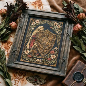 Op de afbeelding: Een ingelijst kunstwerk met een middeleeuwse illustratie van een figuur met schild. De donkere houten lijst heeft gotische details. De afbeelding heeft een donkerblauwe achtergrond met gouden, rode en crèmekleurige bloemen- en bladaccenten. Decoratieve elementen omringen het frame.