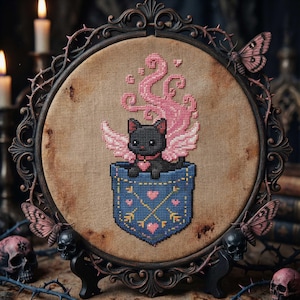 May include: A framed cross-stitch featuring a black cat with pink wings and a heart collar, emerging from a blue pocket adorned with hearts and arrows. The frame is dark with decorative elements, and the background is a neutral tan.