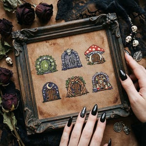 May include: A framed cross-stitch sampler with six fantasy door designs. The doors feature details such as a mushroom roof, a moon and stars, and a skull. The dark brown frame has ornate detailing, and the background is a tan fabric.