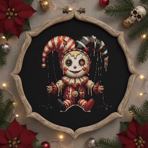 May include: A framed cross-stitch of a creepy jester doll with a red, white, and black color scheme. The doll has a smiling face, a striped hat, and is dressed in a matching outfit. The frame is wooden and the background is black.