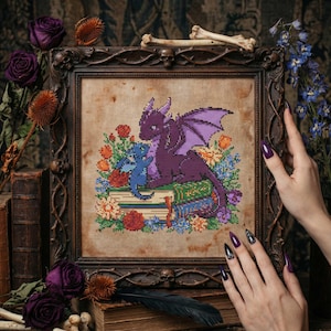 May include: Cross-stitch art of a purple dragon with a blue dragon, resting on books surrounded by flowers. The artwork is in a dark wooden frame, with a vintage aesthetic. The color palette includes purple, blue, green, and orange.