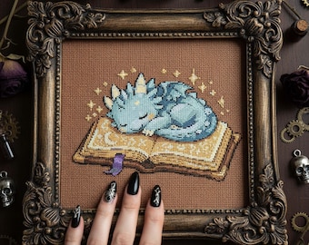 Patrón de punto de cruz de dragón bebé durmiendo: bordado de dragón de fantasía acogedor sobre libro (PDF)