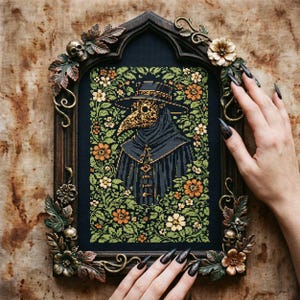 May include: A framed cross-stitch artwork featuring a plague doctor in a black cloak and hat with a gold beak mask, surrounded by flowers. The frame is dark wood with decorative floral and skull accents.