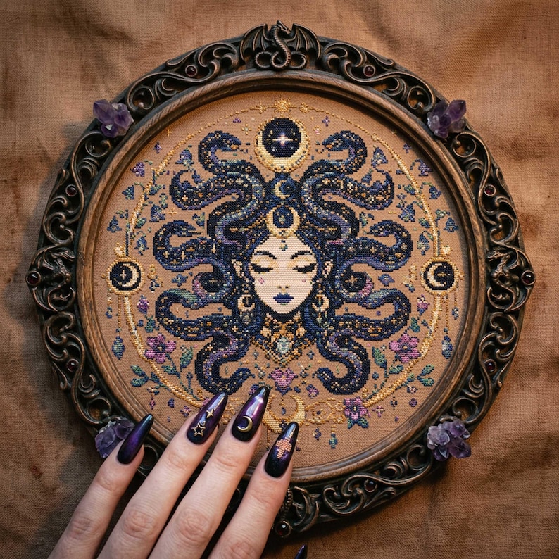 This celestial Medusa cross stitch pattern features a mystical serpent goddess surrounded by flowing cosmic snakes, golden moon symbols, celestial ornaments, and delicate floral accents. Inspired by mythology and dark fantasy aesthetics, the design transforms Medusa into a peaceful moonlit queen filled with elegance and magical energy. Deep navy blue tones blend with soft lavender, dusty pink, and gold celestial details to create an enchanting embroidery composition perfect for gothic home décor
