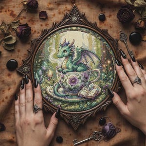 Peut inclure: Point de croix d'un dragon vert dans une tasse à thé, dans une scène de forêt. L'œuvre est encadrée dans un cadre en bois foncé et orné. La tasse et la soucoupe sont décorées de motifs floraux. Le dragon a des ailes violettes.