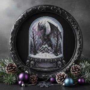 Może przedstawiać: Oprawiona praca haftu krzyżykowego przedstawiająca czarnego smoka wewnątrz kuli śnieżnej. Smok jest osadzony na tle zaśnieżonego górskiego krajobrazu z drzewami, pod fioletowym niebem. Rama jest czarna i ozdobna, z dekoracyjnymi czaszkami u podstawy.