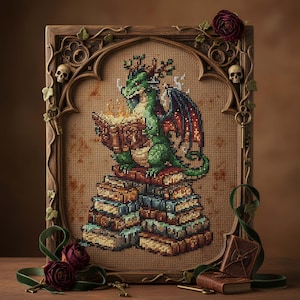 Peut inclure: Broderie au point de croix d'un dragon vert lisant un livre sur une pile de livres. L'œuvre est encadrée dans un cadre en bois avec des éléments décoratifs, dont des crânes et du lierre. Le dragon a des ailes rouges et bleues.