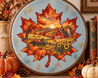 May include: A circular wooden embroidery hoop containing a cross-stitch design of a large maple leaf. The leaf features a rural autumn landscape with a red barn, pumpkins, sunflowers, and a sunset sky against a light blue background.