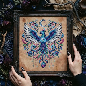 Peut inclure: Broderie au point de croix encadrée représentant un phénix coloré aux ailes déployées, un croissant de lune et des motifs floraux. Le phénix est principalement bleu, avec des détails roses et verts. Le cadre est en bois foncé.