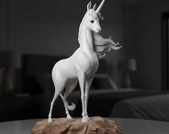 Op de afbeelding: Een witte eenhoornfiguur met een spiraalvormige hoorn en vloeiende manen, staand op een bruine, rotsachtige basis. De eenhoorn heeft blauwe ogen en is gracieus geposeerd. De achtergrond is wazig.