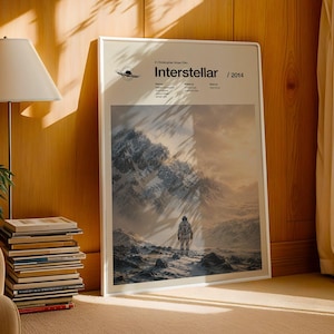 Puede incluir: Un póster rectangular de pared con el título de la película Interstellar, el año 2014 y una escena cinematográfica de un astronauta de pie en un vasto paisaje montañoso nevado. El cartel incluye un pequeño gráfico de un agujero negro.