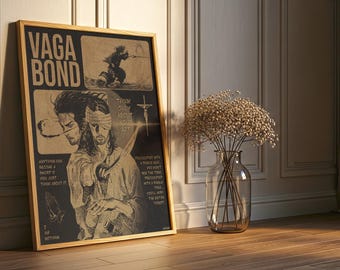 May include: Framed art print with the word "VAGABOND" at the top. The artwork features illustrations of a samurai and a figure with a blindfold, along with text. The print is in a wooden frame and leans against a wall.