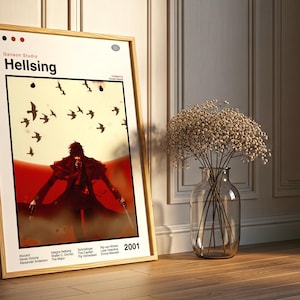 May include: A framed "Hellsing" poster is propped against a wall. The poster displays a character illustration with a red backdrop, birds, and the year 2001. A glass vase with dried flowers is placed on a wooden floor nearby.