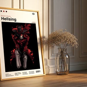 May include: A framed poster with the title "Hellsing" in white lettering. The image shows a character in a red outfit, holding two silver pistols, set against a black backdrop. The poster is propped against a wall.
