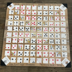 Może przedstawiać: Drewniana gra planszowa z kartami do gry ułożonymi w siatkę. Plansza do gry zawiera tekst "The Game of Sequence" i "Joker". Karty są ułożone w kierach, karach, treflach i pikach.