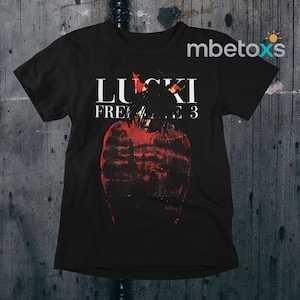 May include: Black t-shirt featuring the text "LUCKI FREAK 3" in white. The shirt has a red graphic design of a person. The shirt is a crew neck and short-sleeved.