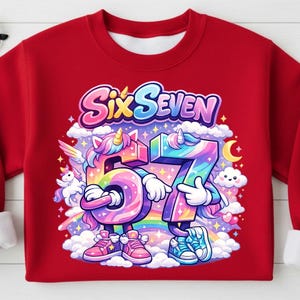 May include: Red sweatshirt featuring a colorful graphic of the numbers "6" and "7" as cartoon unicorns, with the text "Six Seven" above. The design includes a rainbow, clouds, and a crescent moon.