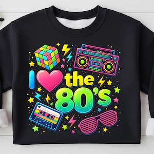 Może przedstawiać: Czarna bluza z kolorową grafiką w stylu lat 80. Projekt zawiera kostkę Rubika, boombox, kasetę i napis "I ❤️ the 80's". Grafika zawiera również różowe serce, błyskawice, gwiazdy i różowe okulary przeciwsłoneczne.
