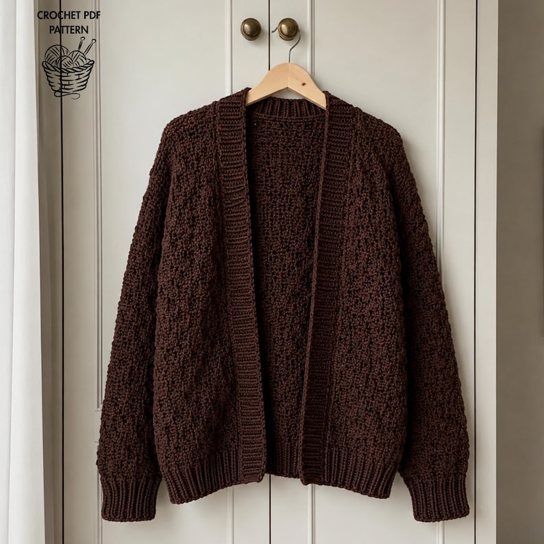 May include: A dark brown open-front cardigan with a textured, chunky knit pattern, long sleeves, and ribbed cuffs and hem. The garment is displayed on a wooden hanger. Text in the upper left corner reads CROCHET PDF PATTERN with an icon.
