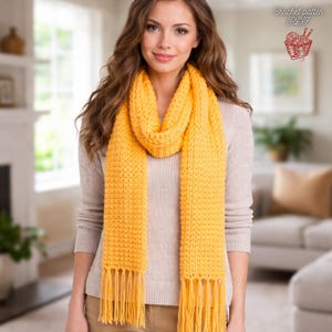 May include: A bright yellow, fringed scarf. The scarf is made of a textured knit material and is draped around the neck. The scarf is a vibrant shade of yellow and has a rectangular shape. The image also includes the text "Crochet pattern PDF".