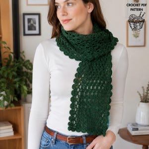 May include: A dark green crochet scarf featuring an openwork stitch pattern and a scalloped edge. The scarf is worn over a long-sleeved white shirt and blue jeans. The image includes text in the upper right corner that reads CROCHET PDF PATTERN.