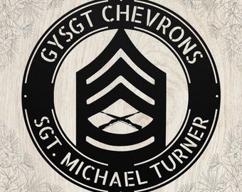 May include: Black metal sign featuring a military rank insignia with the text "GYSGT CHEVRONS" and "SGT. MICHAEL TURNER" in a circular design. The sign has a detailed, cut-out appearance, suitable for display.