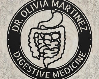 May include: A circular black metal wall sign featuring a central cutout illustration of the human stomach and intestines. The text DR. OLIVIA MARTINEZ is arched across the top, and DIGESTIVE MEDICINE is arched across the bottom in a bold font.
