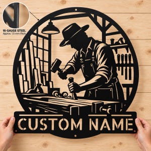 May include: A circular black metal wall sign featuring a silhouette of a woodworker using a mallet and chisel at a workbench. The design includes tools on shelves and a bottom banner with the text CUSTOM NAME. It is made of 16-gauge steel.