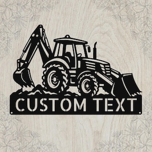 May include: A black metal wall sign featuring a silhouette of a backhoe loader construction vehicle. The design includes a flat base section with the words CUSTOM TEXT in a bold, sans-serif font, positioned directly below the heavy machinery.