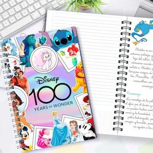 以下が含まれることがあります： ディズニーのキャラクターと「Disney 100 Years of Wonder」の文字が描かれた、カラフルな表紙のスパイラルノート。開いたページには、映画「アラジン」に関するテキストとイラストが表示されています。