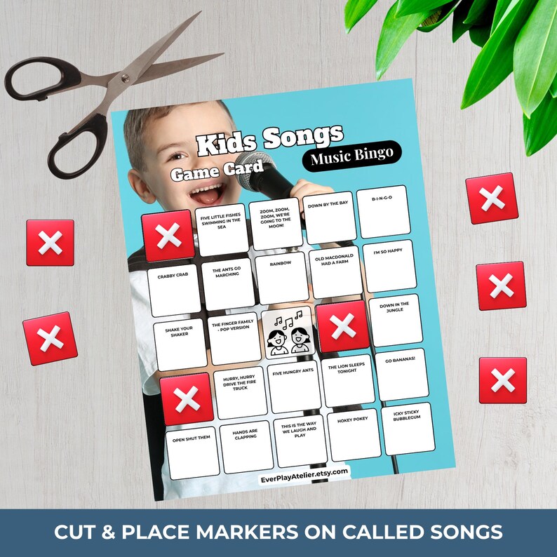 Puede incluir: Una tarjeta de juego de bingo musical para ni&ntilde;os con un ni&ntilde;o sosteniendo un micr&oacute;fono. La tarjeta presenta t&iacute;tulos de canciones y marcadores "X" rojos. Tijeras y hojas verdes tambi&eacute;n est&aacute;n en la imagen. El texto dice "Kids Songs Music Bingo".