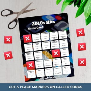 Puede incluir: Una tarjeta de juego negra titulada "2010s Hits Game Card" con t&iacute;tulos de canciones, marcadores "X" rojos y tijeras. La tarjeta presenta un gr&aacute;fico de tel&eacute;fono inteligente y el texto "Cut & Place Markers on Called Songs".