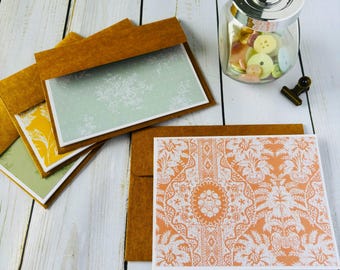 May include: Set of four blank greeting cards with brown envelopes. The cards feature different patterned designs in shades of green, yellow, and orange.